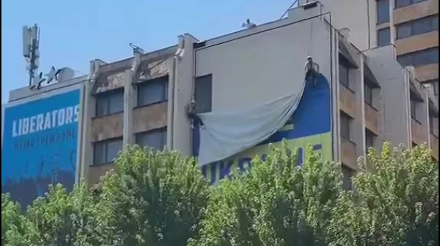 Великий синьо-жовтий український банер на будівлі у центрі Приштини та момент його демонтажу
